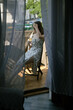 Girl through the curtains posing on the balcony with a glass