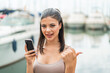 © luismolinero - Young pretty woman at outdoors using mobile phone and pointing to the lateral
