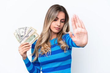 Canvas Print - Young Uruguayan woman taking a lot of money isolated on white background making stop gesture and disappointed