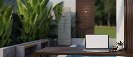 Wall Mural - A laptop mockup on a table in a beautiful tropical home's outdoor terrace or courtyard