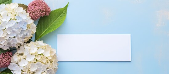 Aufkleber - A top-down view of a beautiful composition featuring hortensia flowers and a blank card on a light blue