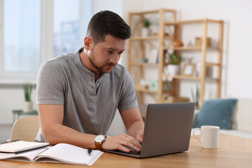 Poster - Man working on laptop at wooden desk in room