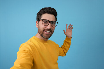 Canvas Print - Smiling man taking selfie on light blue background