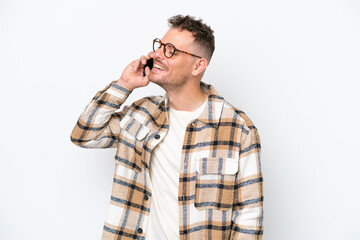 Wall Mural - Young caucasian handsome man isolated on white background keeping a conversation with the mobile phone