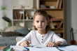 © Mediaphotos - Portrait of little boy sitting at desk with books and looking at camera, he studying at home