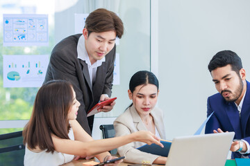 Asian Indian multinational professional successful bearded male businessman explaining discussing brainstorming with female businesswomen colleagues in formal business suit in office meeting room