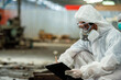 © BESTIMAGE - man in protective gear inspector chemical gas leak spill with safety face mask PPE suit in area closed barricade tape. industrial worker working area infected chemical leak spill cross stripe ribbon