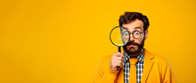 Portrait Of Funny Man Looking Through Magnifying Glass Searching Or Investigating Something Standing In Sweater Against Yellow Copy Space Background.