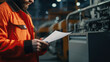 © Malika - Man in an orange jacket is reading a sheet of paper at the industrial plant
