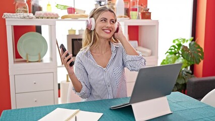 Poster - Young blonde woman listening to music dancing at dinning room