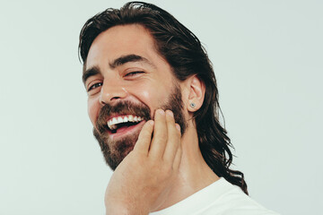Wall Mural - Portrait of a happy man with a beard and radiant skin smiling in a studio