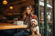 Young caucasian woman sitting with dog in pets friendly cafe