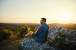 © baranq - Adult man enjoying sunset sitting on top of the mountain