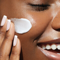 skin care beauty portrait. cream smear. close up portrait of african ametrican woman is applying a s