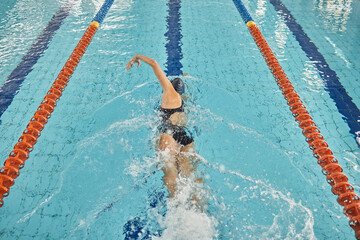 Person, freestyle and swimming in pool for sports competition, challenge and fitness training. Athlete, woman and swimmer in workout exercise for water race stroke, speed and triathlon championship