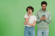 © Drobot Dean - Cheerful woman talking on mobile phone while her boyfriend is texting on his mobile phone isolated over green wall