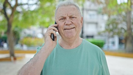 Sticker - Middle age grey-haired man smiling confident talking on the smartphone at park