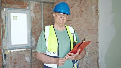 Wall Mural - Middle age grey-haired man builder smiling confident reading document on clipboard at construction site