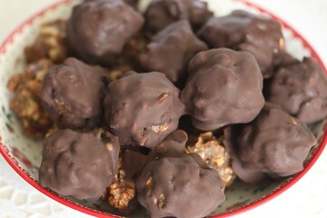 Canvas Print - Homemade candy made from nuts and dried fruits. Some are covered in chocolate. They lie on a plate.