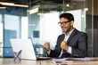 © Liubomir - Young successful arab businessman at workplace inside office, man in business suit with laptop celebrating victory received online win notification, boss winner rejoices and celebrates triumph.
