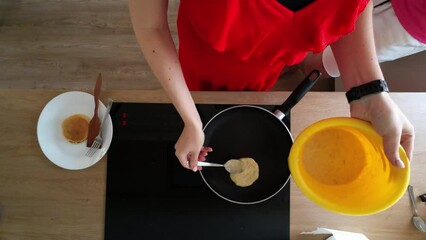 Poster - Top view of female hands making pancake on a hot pan