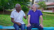 © Marco - Two diverse senior talking and laughing sitting on park bench in Brazil. Candid authentic people real life laugh and smile in old age retirement golden years