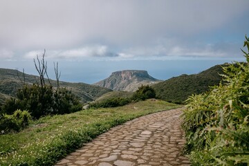 Poster - Idyllic pathway leading to a tranquil mountain in the far distance