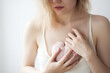 Young lovesick woman holding a blush colored heart to her chest