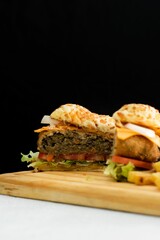 Sticker - Closeup shot of a burger cut in half presented on a wooden cutting board.