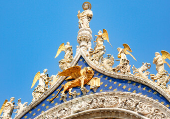 Wall Mural - Saint Mark and golden lion statue, symbol of Venice, on the top of the facade of the Basilica di San Marco, Venice Italy