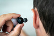 © diy13 - Sideways portrait of smiling young man listening to music or radio, uses modern wireless earphones, wearing blue t-shirt. insert earphone into the ear