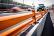 Close-up of a safety barrier being set up on a busy highway with a background of moving traffic.
