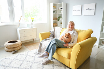 Wall Mural - Mature woman with Pomeranian dog sitting on sofa at home