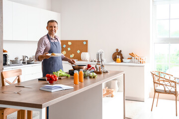 Canvas Print - Mature man with fried vegetables in kitchen