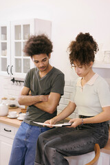 Wall Mural - couple man woman are sitting on table in kitchen paying electricity and rent bills. African American young married person in kitchen count expenses on calculator. financial obligations mortgage loan 