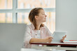© LIGHTFIELD STUDIOS - Side view of smiling teen schoolgirl holding digital tablet and looking away during lesson in class
