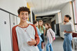 © LIGHTFIELD STUDIOS - happy boy with braces holding smartphone and looking at camera during break in school hallway