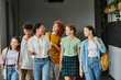 © LIGHTFIELD STUDIOS - cheerful african american teacher walking with teenage students in hallway of school, education