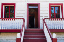 Entrance Staircase Of A Traditional Wooden House In North America. White With Red Railing On White House
