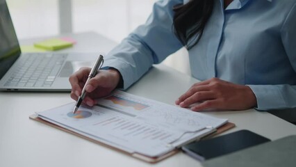 Poster - Young smart Asian businesswoman analyzing the document while working in the office room.