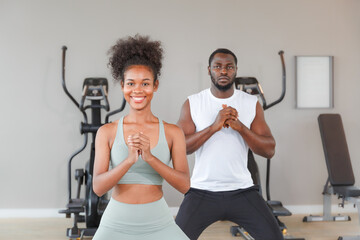 Wall Mural - Young sporty looking man practicing yoga lesson with trainer standing together while exercising in the gym