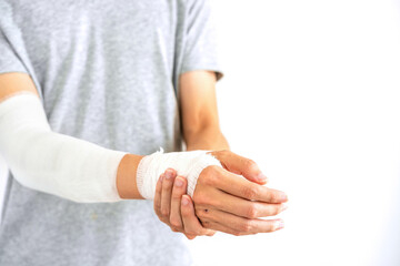 Wall Mural - Young man with gauze bandage wrapped around injury hand on white background