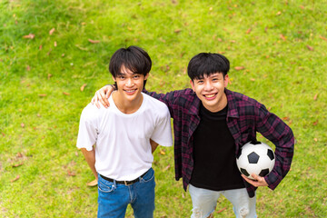 Portrait of Young Asian man playing football together with friends at home backyard. Happy people enjoy and fun outdoor lifestyle with sport workout exercise together on summer holiday vacation.