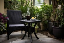 A Home Patio Adorned With Garden Furniture Made Of Black Plastic, Featuring A Small Zen Table Fountain That Adds A Soothing Touch. In The Background, Real Grape Vines Are Seen, Bearing Luscious Grapes