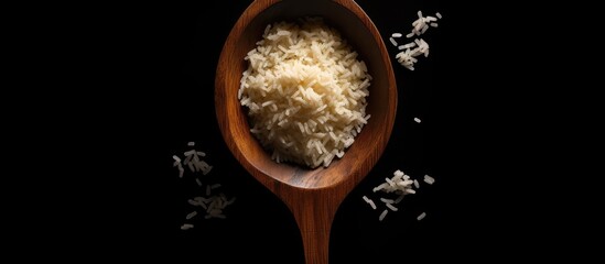 Wall Mural - uncooked Surti Kolam rice with a wooden spoon on a black background. There is empty space for text