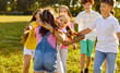 © Studio Romantic - Group of joyful children are walking and having fun together in green park and hugging each other. Kids laugh loudly as they run around park on warm summer day. Children and friendship concept.
