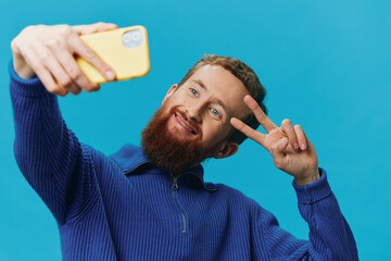 Portrait of a man with a phone in his hands blogger takes selfies, on a blue background. Communicating online social media, lifestyle