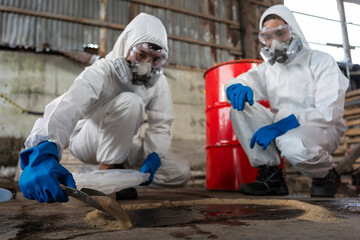 a team of two chemists, wearing ppe suits and gas masks, recover a deadly chemical spill on the fact