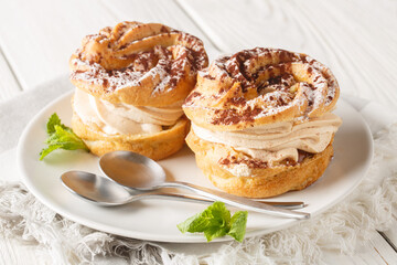 Canvas Print - Paris Brest choux pastry cakes with nut cream filling closeup on a plate on the wooden table. Horizontal