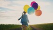 © maxximmm - little girl runs with balloons in the park in nature. happy family holiday birthday kid dream concept. a little girl sun with colorful balloons runs with her back along the road in the field park